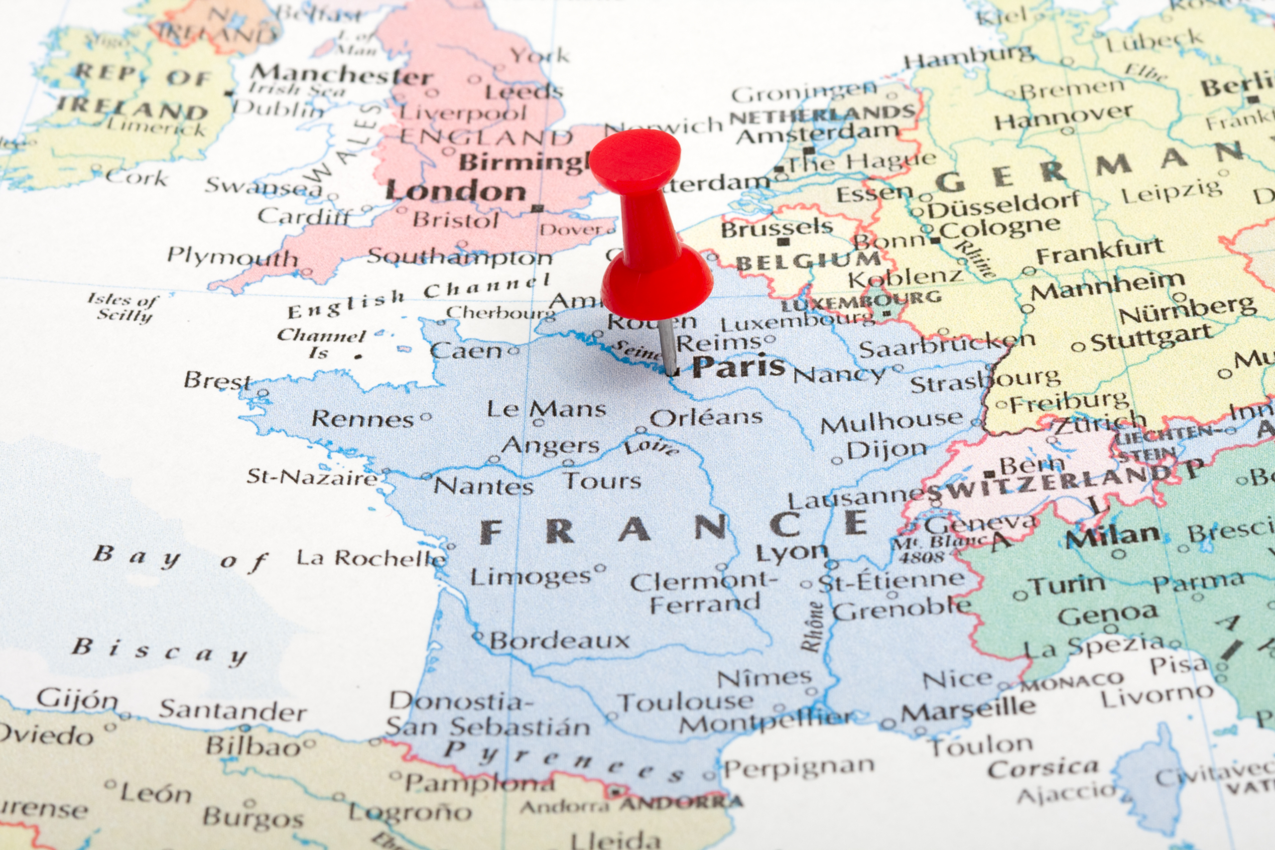A red pushpin is placed on Paris on a map of Europe, highlighting France.