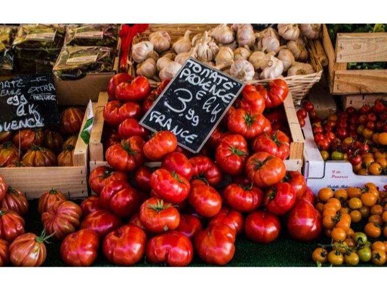Tomates Provence and heirloom tomatoes at a market, with garlic and other produce in the background.