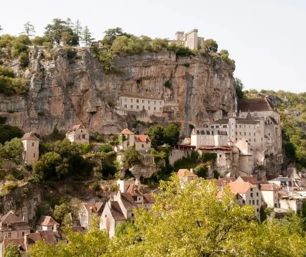 Medieval village built into a steep cliff face, with buildings clustered on terraces and a castle at the summit.