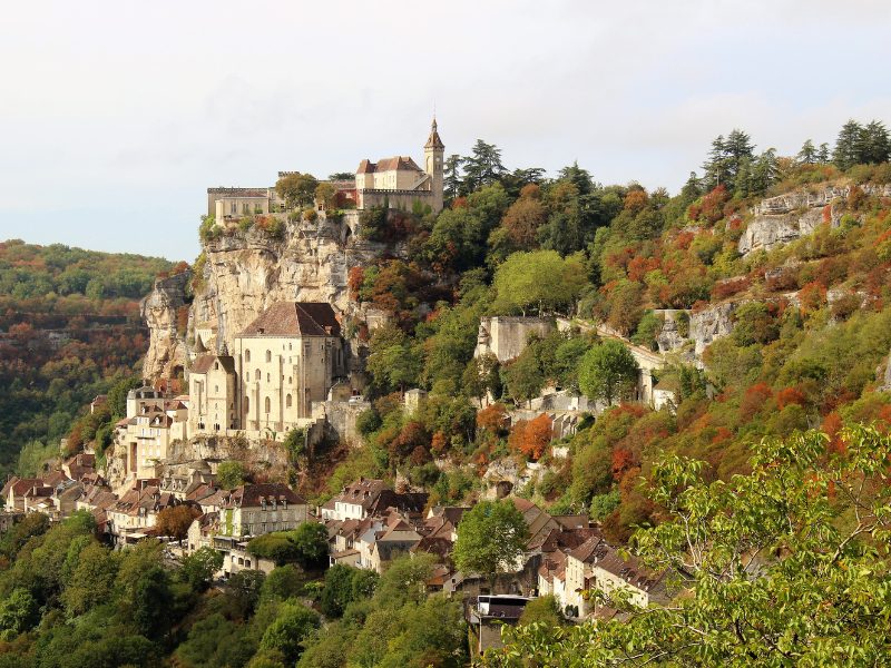 Medieval village of Rocamadour built into a cliff face, with autumn foliage.