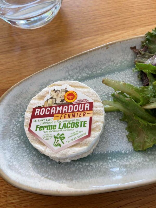 Rocamadour Fermier cheese from Ferme Lacoste, made with raw milk, on a plate with salad.