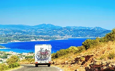 Camper van driving coastal road view of beaches and bay in distance