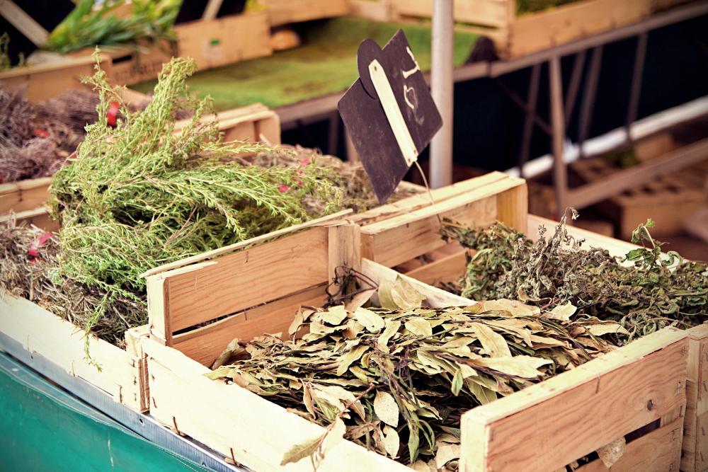 Crates of fresh herbs and dried bay leaves at a market stall