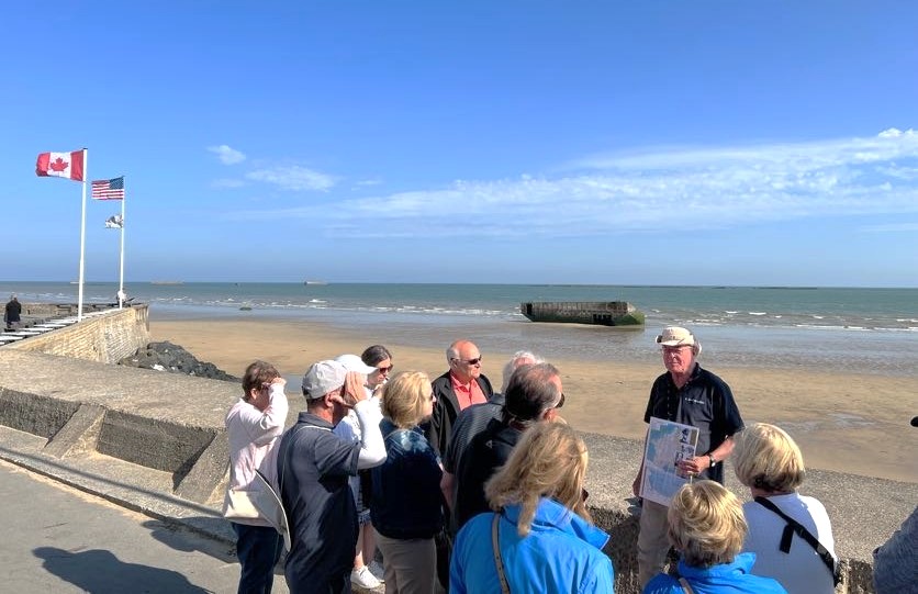 Guide explains D-Day ww2 history in Normandy at Mulberry B off the coast of Arromanches-les-Bains, France