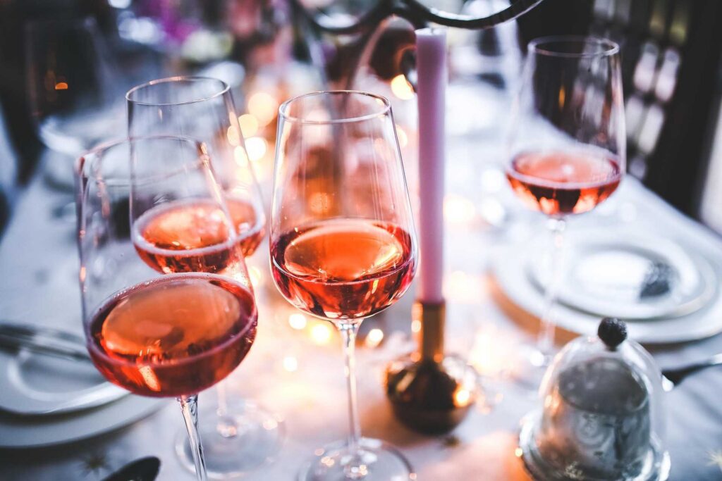 Glasses of Provence rosé on a dinner table with plates and candles out of focus in background