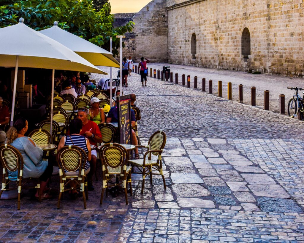 Café terrace on a cobbled street beside the medieval ramparts of Aigues-Mortes in the evening